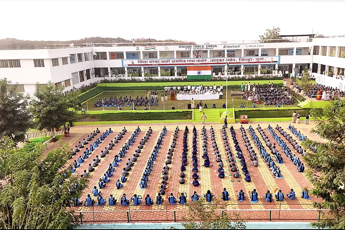 The Zilla Parishad primary school at Dhanore seen from above, with students seated in rows in the yard.