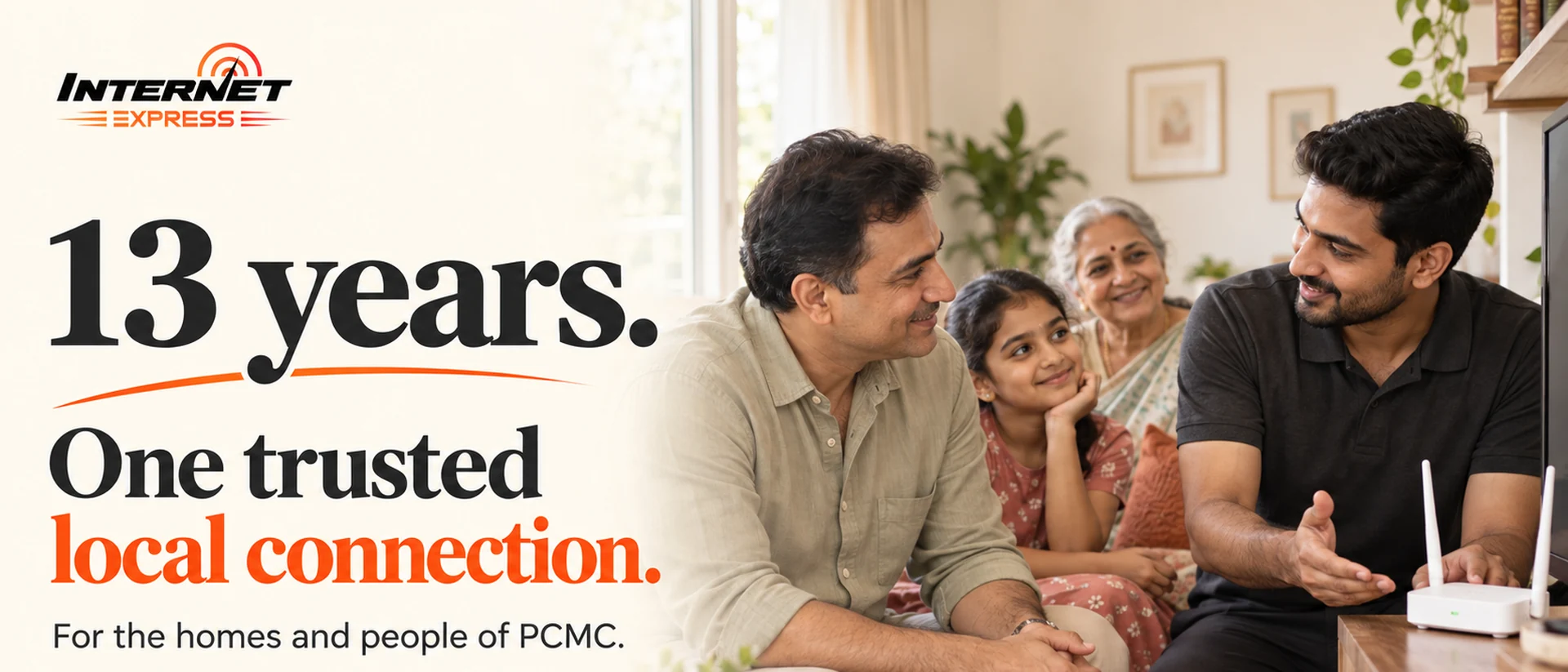 Three generations of a family on a sofa talking with an Internet Express engineer beside their router. Caption: 13 years — one trusted local connection, for the homes and people of PCMC.
